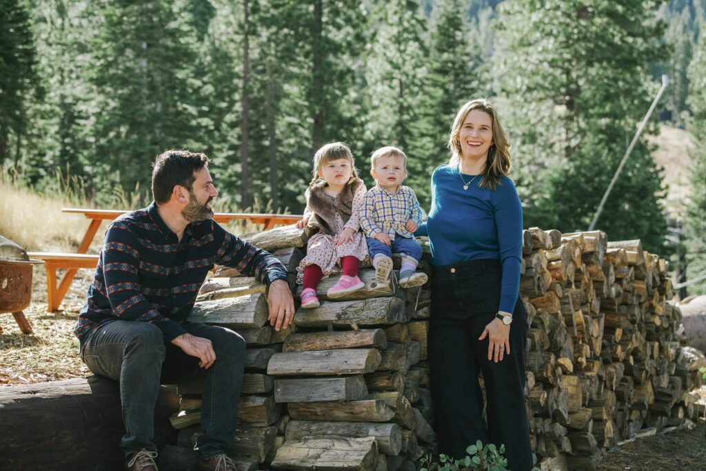family portrait with two small kids on top of wood pile