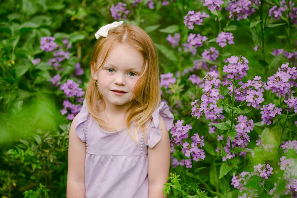 Truckee family photographer close up image of a girl with red hair in the pink flowers and bow in her hair