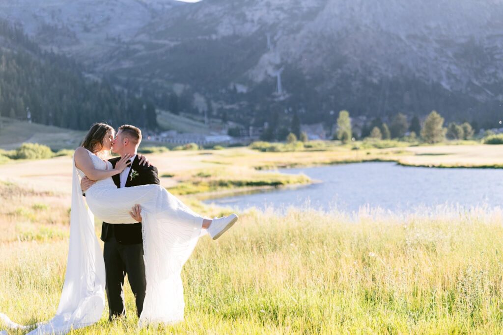 Groom with bride in his arms in front of tram face at palisades Tahoe from a wedding at Everline resort