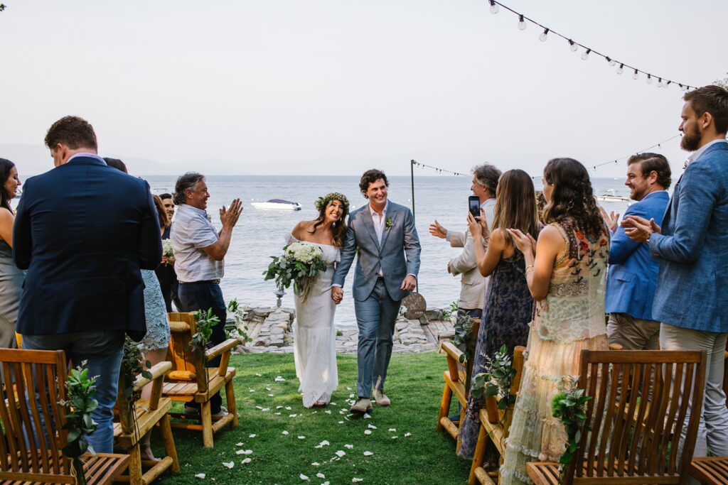 Lake Tahoe micro wedding Just Married feels with bride and groom walking down mini aisle at lakefront private residence on Lake Tahoe and loved ones