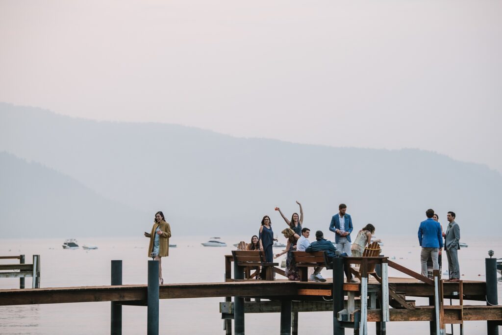 candid guests cocktail hour on pier during intimate wedding at lake Tahoe private residence