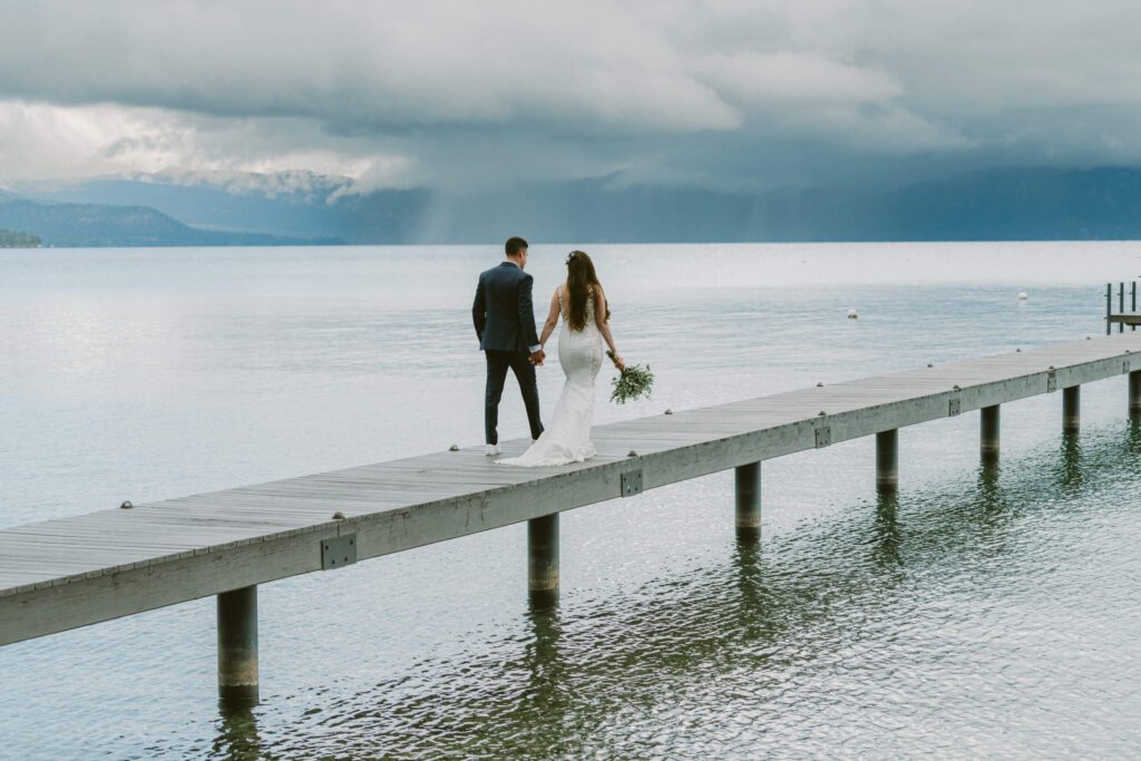 Light rain , dramatic skies for this bride and groom walking on their pier on this private Lake Tahoe lakefront estate.