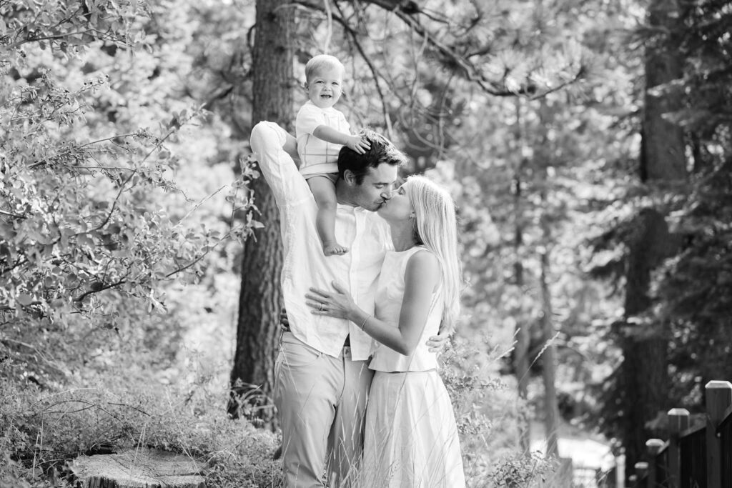 Black and white image of couple with baby on top of dad's shoulders