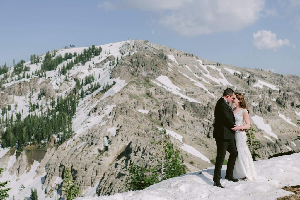 one of my favorite Lake Tahoe mountain wedding venue, Sugar Bowl where we have a bride nad groom on top of Disneyy with snowcap mountains in the background