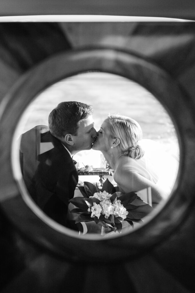 Bride and Groom kissing through a round window on a boat in Lake Tahoe docking at this Lake Tahoe Lakefront wedding venue Garwoods Tahoe