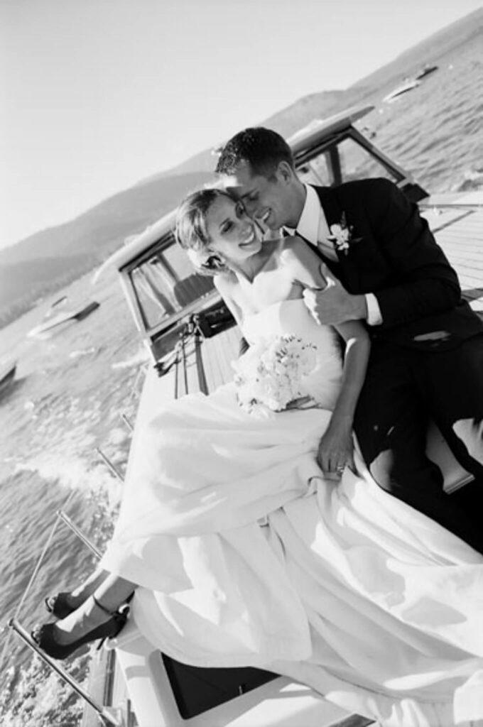 Film image of bride and groom on the front of a boat snuggling doing a victory lap in front of guests at a Chamber Landing wedding