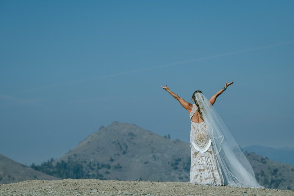 Editorial photographer Annie X Photographer capture of bride hands in the air facing Lake Tahoe at their wedding at top of Palisades Tahoe