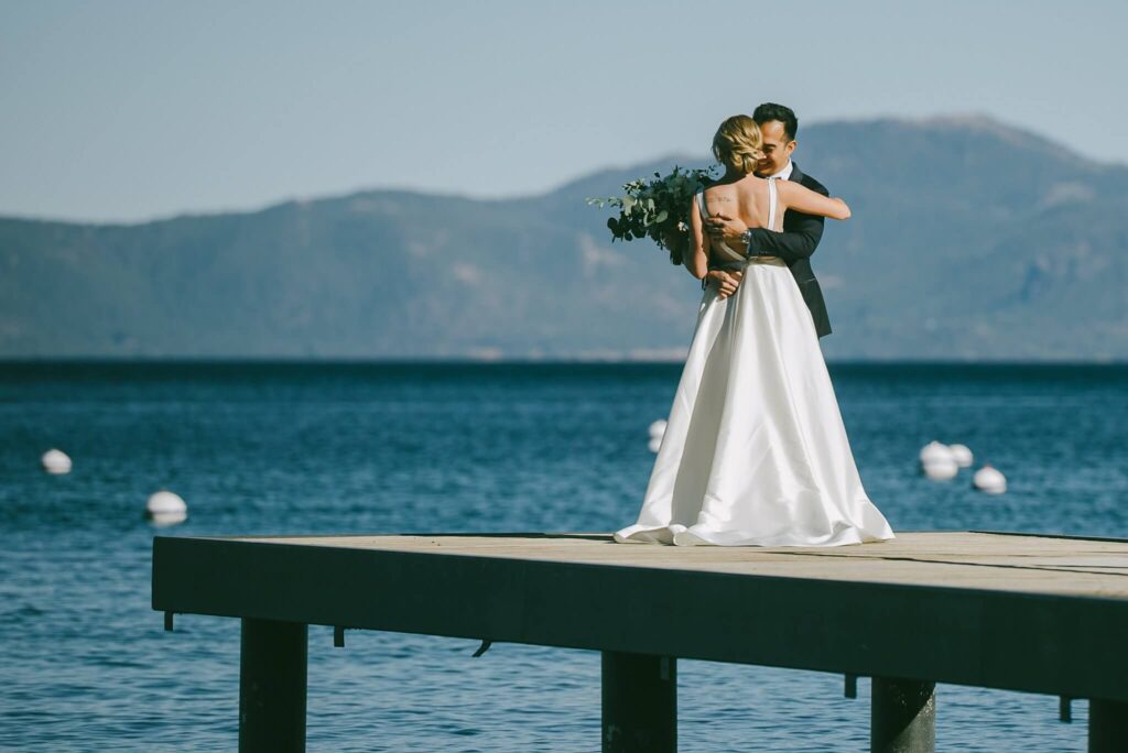 A bride and groom sharing a private first look on a wooden pier at Lake Tahoe with the lake and mountains in the background