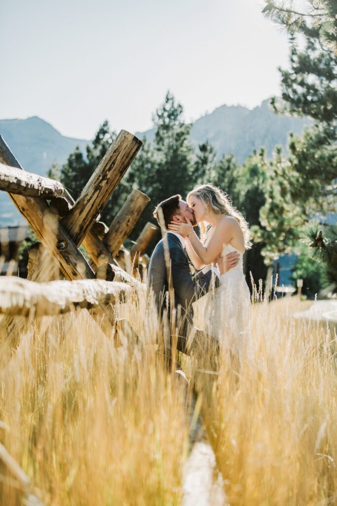 Palisades Tahoe fence with bride and groom kissing in tall fall grass