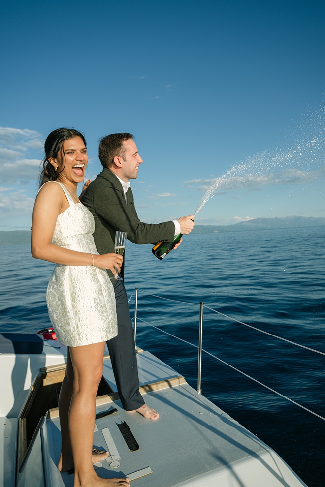 Intimate Lake Tahoe boat wedding on the water at sunset with bride and groom popping just married champagne for toasts with family