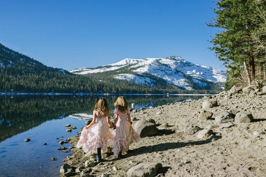 Twin girls walking beach on Donner lake during winter captured by Truckee family photographer Annie X Photographie