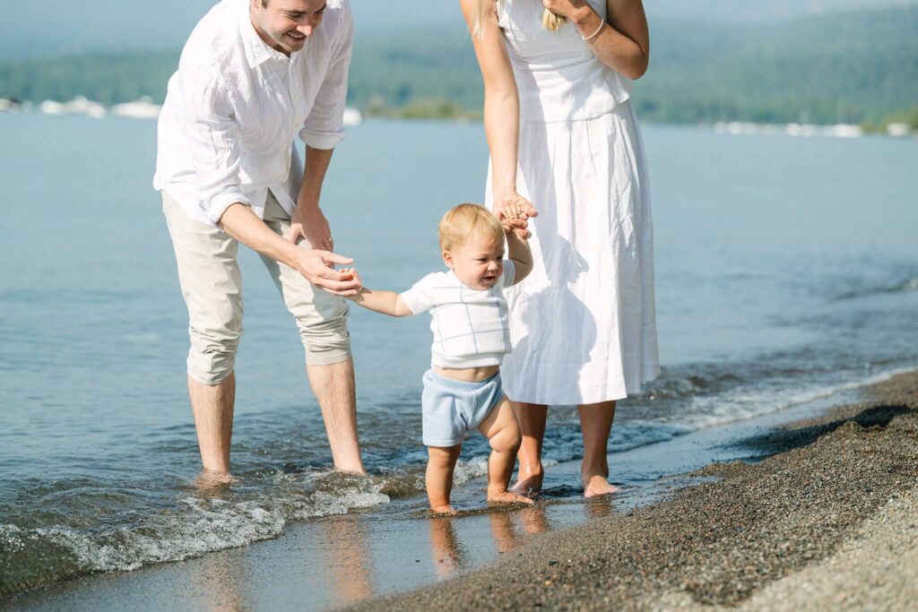 How Often to Take Family Photos in  Lake Tahoe here a family on a summer morning at the lake with baby all dressed in white