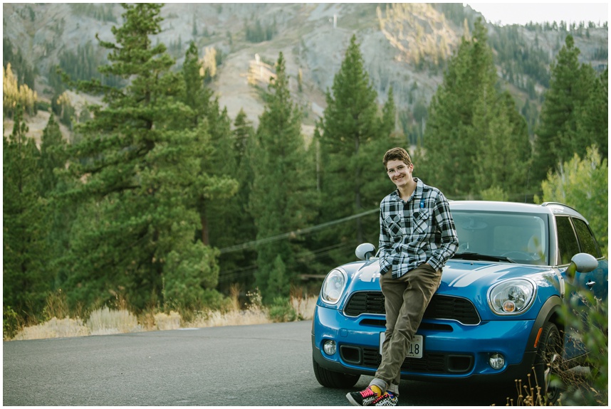 Senior photo in Tahoe with mini Cooper parked on a mountain road in Palisades Tahoe during golden hour