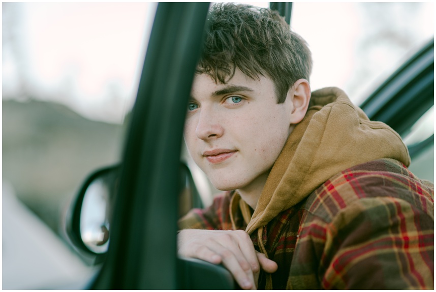 Senior photo in Tahoe with Tacoma parked on a mountain road during golden hour, looking at camera close up