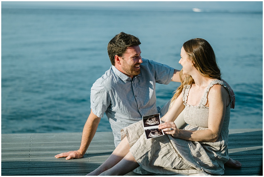 Lake Tahoe family photographer capturing candid portraits on a private pier at sunset with this young couple awaiting their first baby