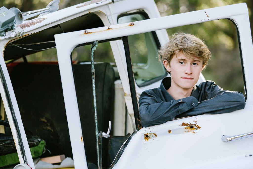 Truckee senior with old antique car looking at camera in Tahoe