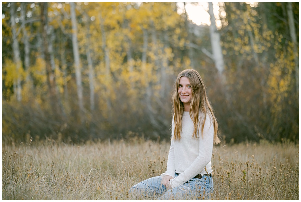 Truckee senior girl sitting in a meadow during her fall senior portrait session photographed by Tahoe senior photographer Annie X