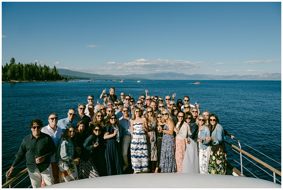 Friends gathered on front boat deck while cruising  along the West Shore during birthday cruise celebration group photo and toast