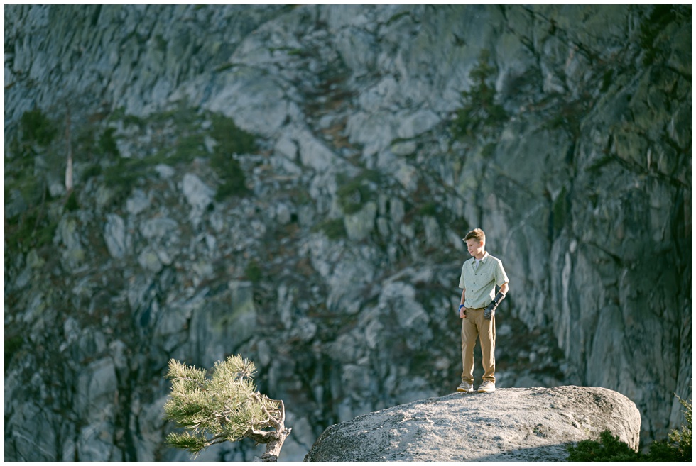 Truckee family photographer capturing a boy up on donner summit standing on granite rock