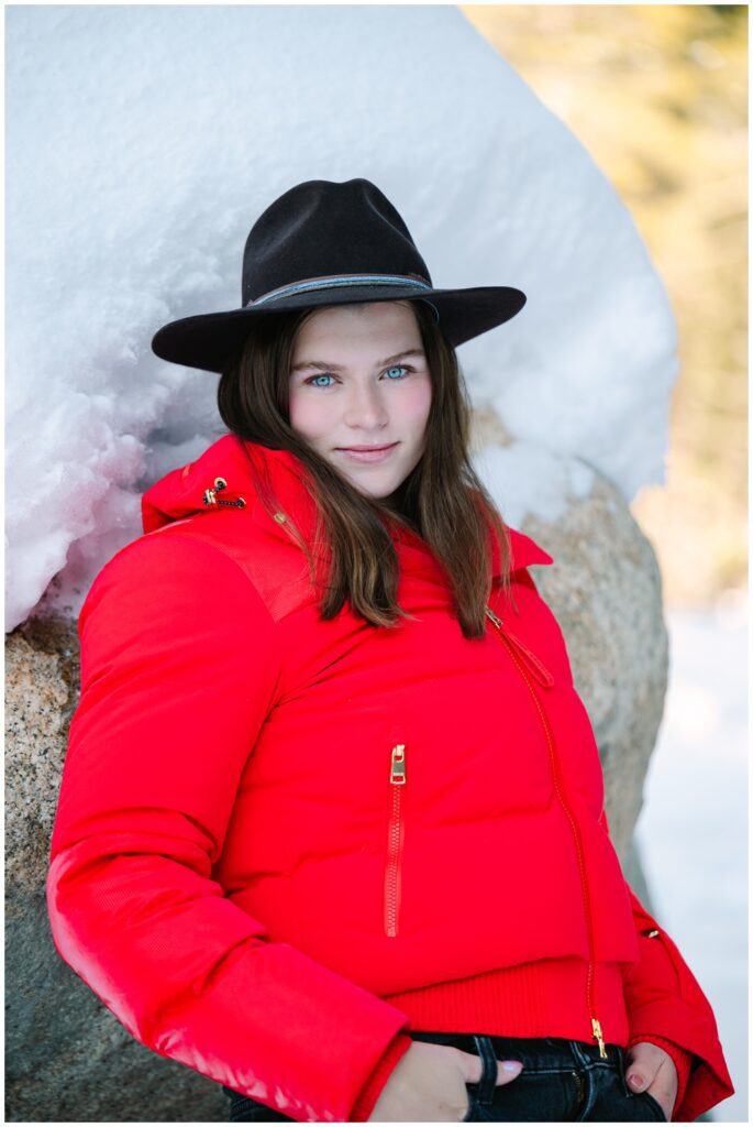 Daughter in a red coat and cowboy hat looking at the camera during her Truckee family photo session for the family Valentine's cards.
