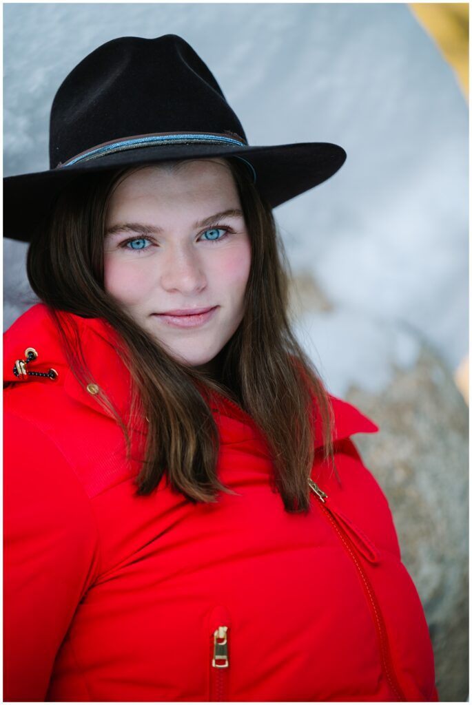 close up of girl wearing red jacket and black cowboy hat and blue eyed in winter