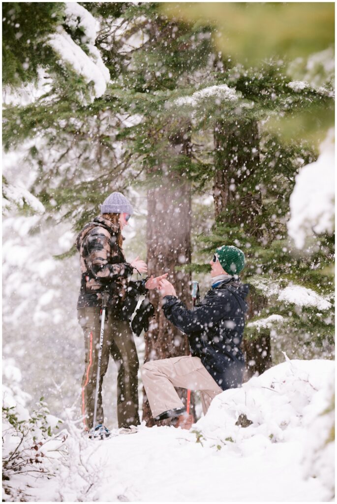 Groom to be on one knee proposing during a blizzard in Tahoe captured by Truckee proposal photographer Annie X Photographie