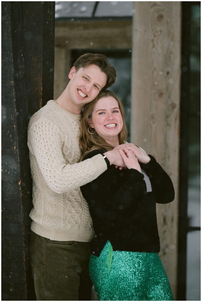 Couple facing camera in entrance of family home in martis Camp Tahoe bride to be wearing sequined green pants for a touch of fun