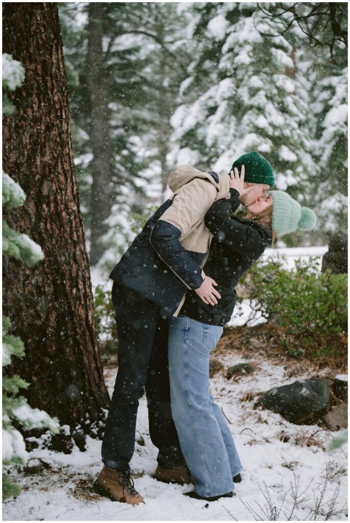couple kissing full length amongst snowflakes falling