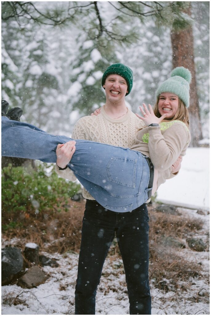 Groom to be holding his fiance in his arms while she is showing off her ring