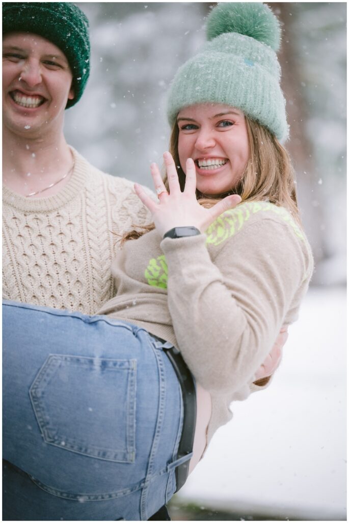 Happy bride to be showing off engagement ring during a snowstorm