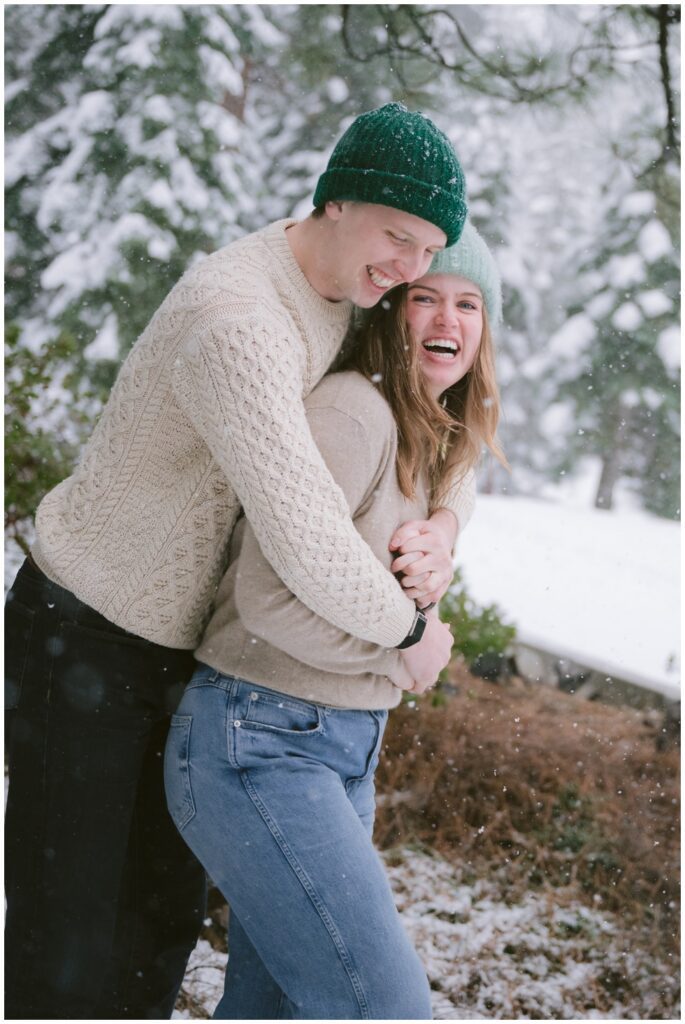 couple hugging laughing together during a blizzard engagement session