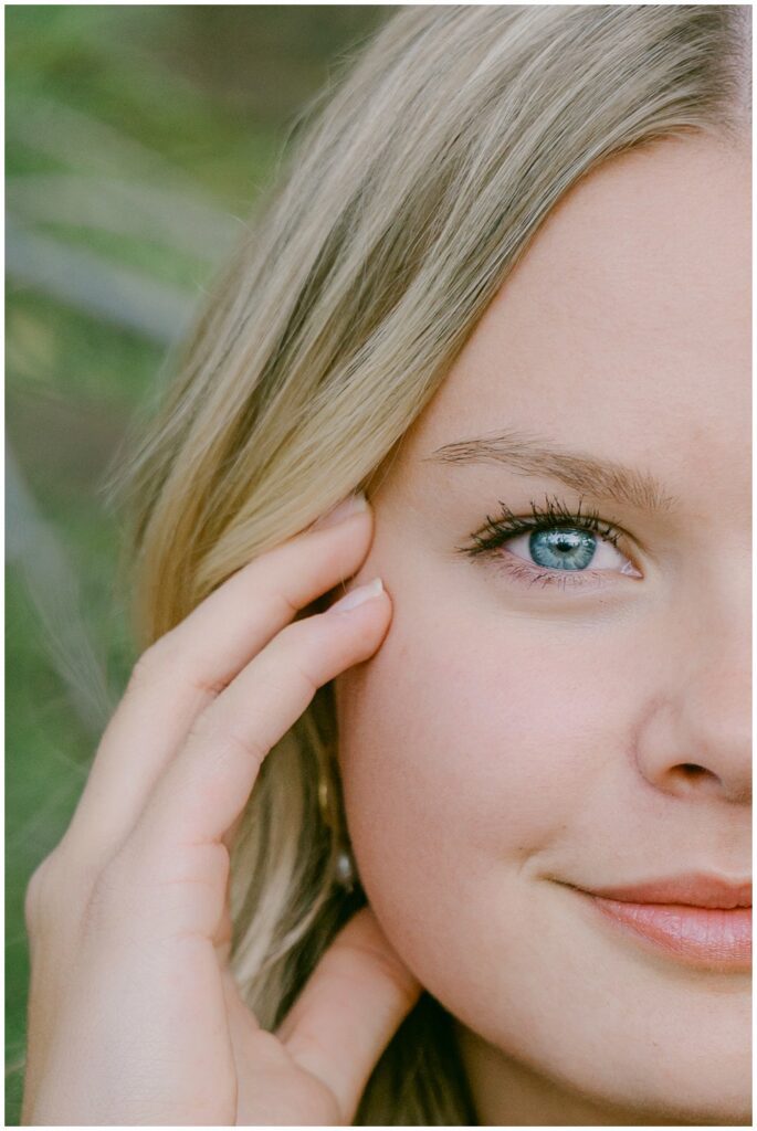 Senior portraits Lake Tahoe editorial half face close up portrait of senior girl with single blue eye and pine tree bokeh background West Shore California Truckee senior photographer